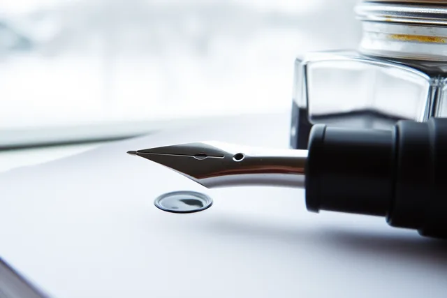 Fountain pen nib on notebook paper beside an open ink bottle in dry winter air. Why Canadian winters and indoor heating change your ink flow and paper storage